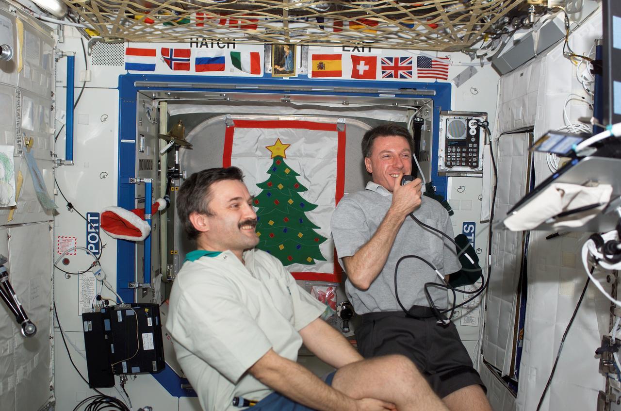 ISS008-E-10737 (28 Dec. 2003) --- Astronaut C. Michael Foale (right), Expedition 8 mission commander and NASA ISS science officer, and cosmonaut Alexander Y. Kaleri, flight engineer, conduct a teleconference with the Moscow Support Group for the Russian New Year celebration, via Ku- and S-band, with audio and video relayed to the Mission Control Center (MCC) at Johnson Space Center (JSC). Kaleri represents Rosaviakosmos.