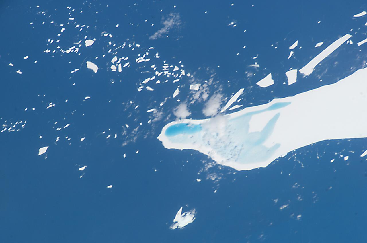 ISS008-E-12555 (22 January 2004) --- This photo of melt-water pooled on the surface of iceberg A-39D, a 2 x 11 kilometers iceberg currently located near South Georgia Island, was taken by an Expedition 8 crewmember on the International Space Station (ISS). The different intensities of blue are interpreted as different water depths. From the orientation of the iceberg, the deepest water (darkest blue) lies at the westernmost end of the iceberg. The water pools have formed from snowmelt &#0150; late January is the peak of the southern summer. This iceberg was part of the original A-38 iceberg that calved from the Ronne Ice Shelf in October 1998. Originally the ice was between 200 and 350 meters thick. This piece of that iceberg is now probably about 150 meters thick, with around 15 meters sticking up above the surface of the water.