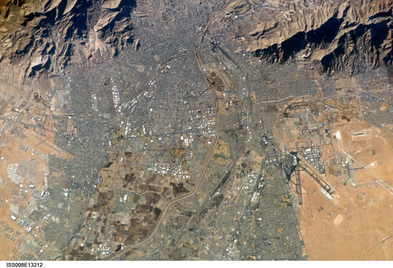 ISS008-E-13212 (26 January 2004) --- This image of the El Paso-Juarez area on the U.S.-Mexico border, photographed by an Expedition 8 crewmember, is the 100,000th photograph of Earth that astronauts have taken from the International Space Station (ISS). The Rio Grande can be seen meandering through the area, forming the boundary between the sister cities of El Paso, Texas and Juarez, Chihuahua. North is to the right in this image, and the setting sun has cast the east side of the Sierra Juarez and Franklin Mountains into shadow.