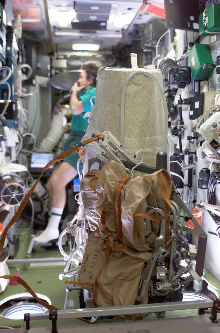 ISS008-E-17183 (24 February 2004) --- This image shows a close-up view of the extravehicular activity (EVA) bundle in the Zvezda Service Module on the International Space Station (ISS). The Matroshka experiment package is shrouded (aft) with the brown carry bags for the CKK hardware (fwd) along with tools and other needed items. It is all bundled to a Russian EVA integrated equipment carrier. Cosmonaut Alexander Y. Kaleri, flight engineer representing Russia&#0146;s Federal Space Agency, is in the background.