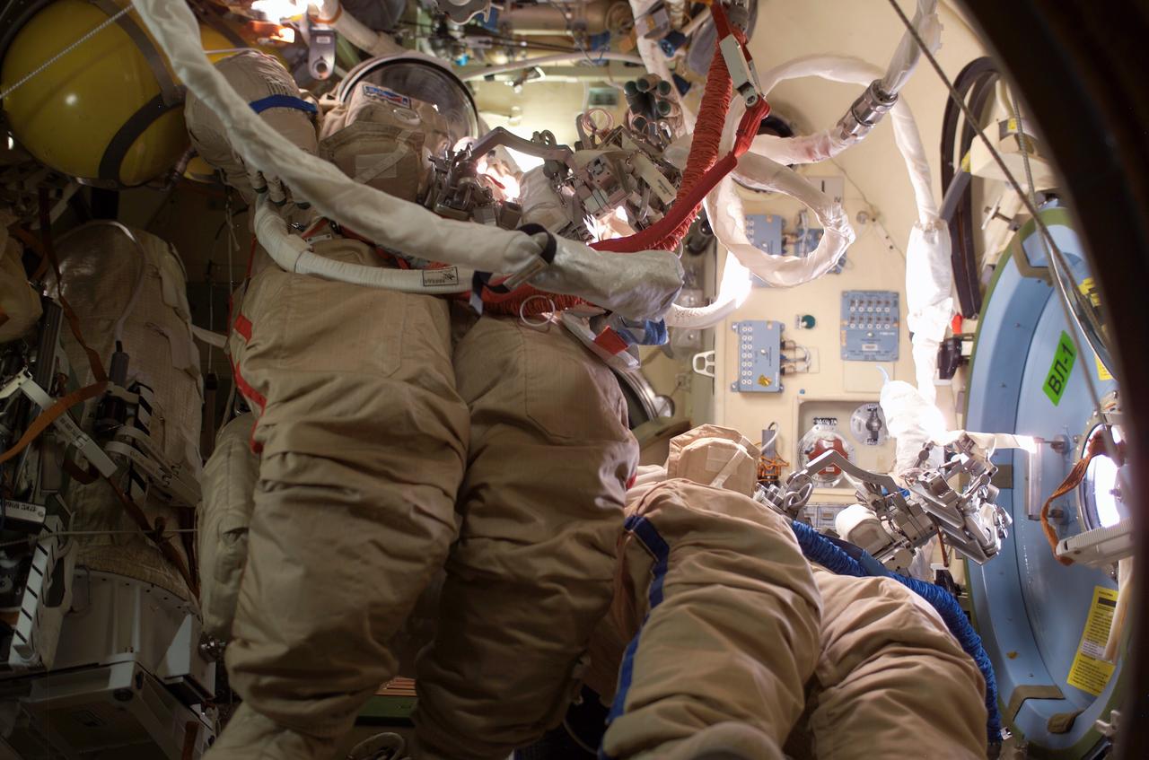 ISS008-E-17187 (26 February 2004) --- This view shows a duo of Russian Orlan space suit lower torsos stowed in the Pirs Docking Compartment on the International Space Station (ISS) following completion of an extravehicular activity (EVA) conducted by the Expedition 8 crew. A tool caddy is attached to each suit.