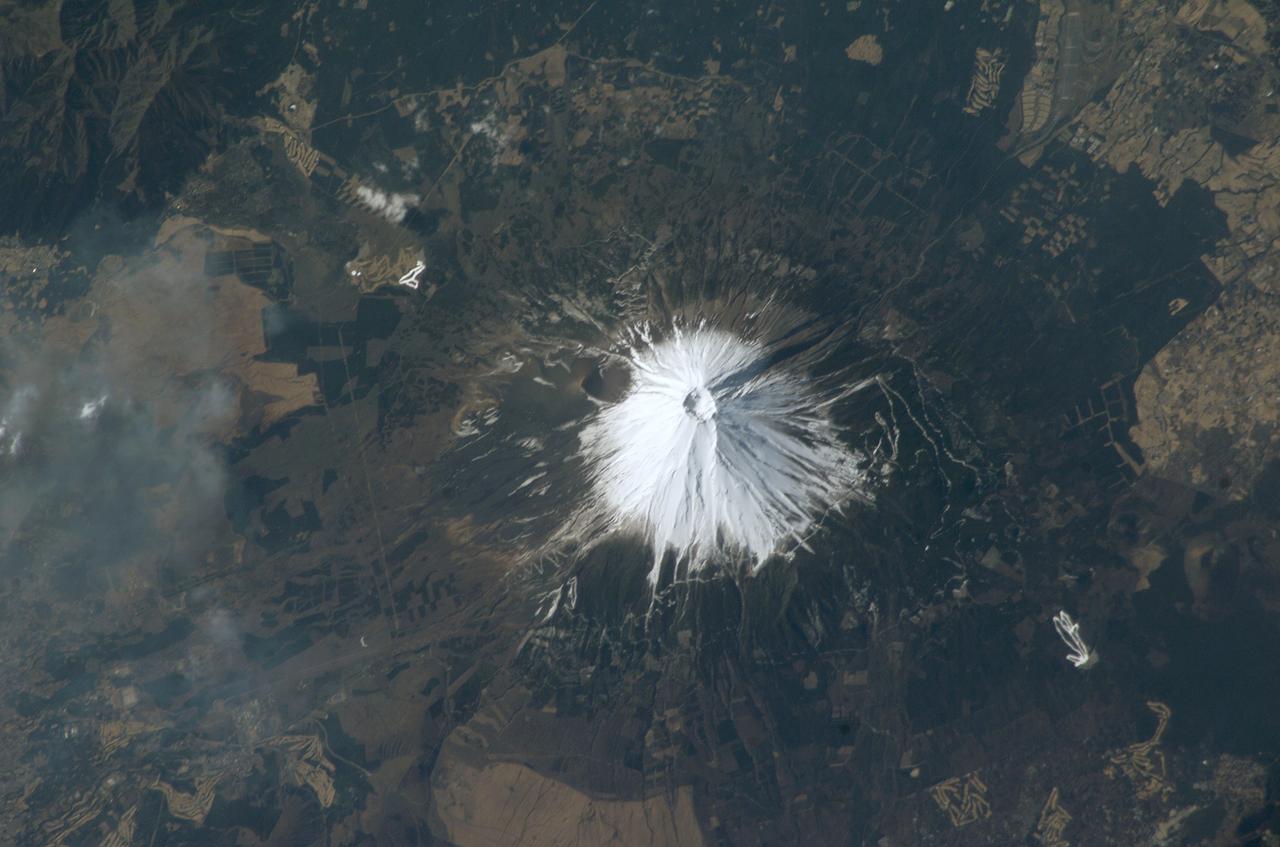 ISS008-E-17326 (28 February 2004) --- Mt. Fuji, Japan’s tallest volcano (3776 meters) and national symbol, is featured in this photo taken by an Expedition 8 crewmember onboard the International Space Station (ISS). Fuji is located about 110 kilometers (70 miles) west-southwest of Tokyo in central Honshu, Japan. The summit crater is about 250 meters deep, with a diameter of about 500 meters. Fuji last erupted in 1707 from Hoei crater, a vent on the mountain’s southeastern flank. When this image was taken, the winter snow cover highlighted trails, roads and other clearings above a certain elevation. Developments on Fuji’s lower flanks, which include military installations and tourist resorts, remained snow-free.