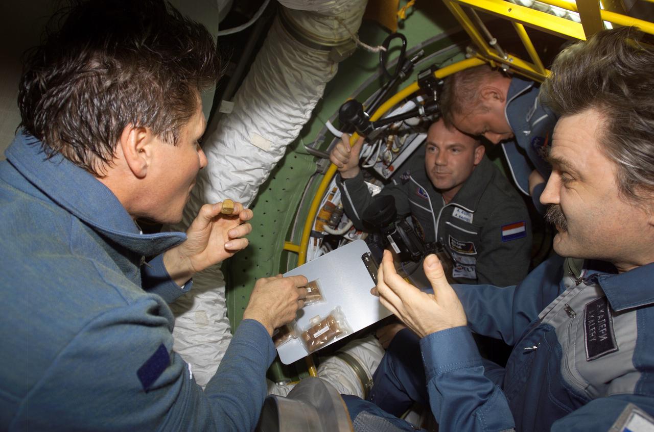 ISS008-E-21947 (21 April 2004) --- Cosmonaut Gennady I. Padalka (left), Expedition 9 commander, partakes of a traditional greeting of salt and bread presented by cosmonaut Alexander Y. Kaleri (right), Expedition 8 flight engineer, both representing Russia&#0146;s Federal Space Agency. European Space Agency (ESA) astronaut Andre Kuipers of the Netherlands and astronaut Edward M. (Mike) Fincke, Expedition 9 NASA ISS science officer and flight engineer, are visible in the background.