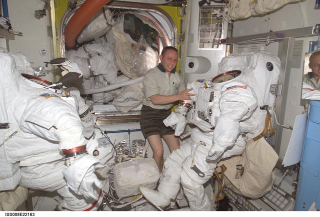 NASA image: Fincke poses with stowed EMUs and EVA equipment in the Quest A/L during EXP 8 / EXP 9