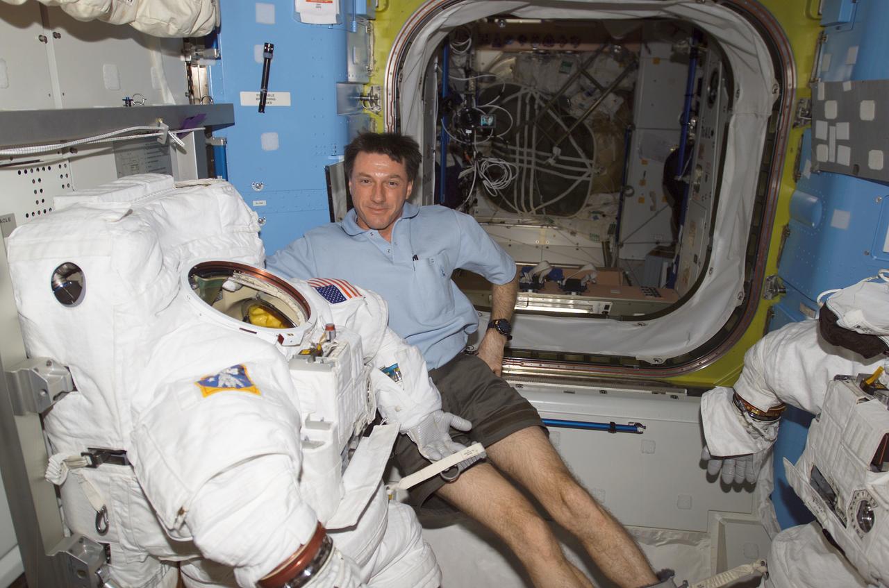 ISS008-E-22166 (25 April 2004) --- Astronaut C. Michael Foale, Expedition 8 commander and NASA ISS science officer, floats near a stowed Extravehicular Mobility Unit (EMU) spacesuit in the Equipment Lock of the Quest airlock on the International Space Station (ISS).