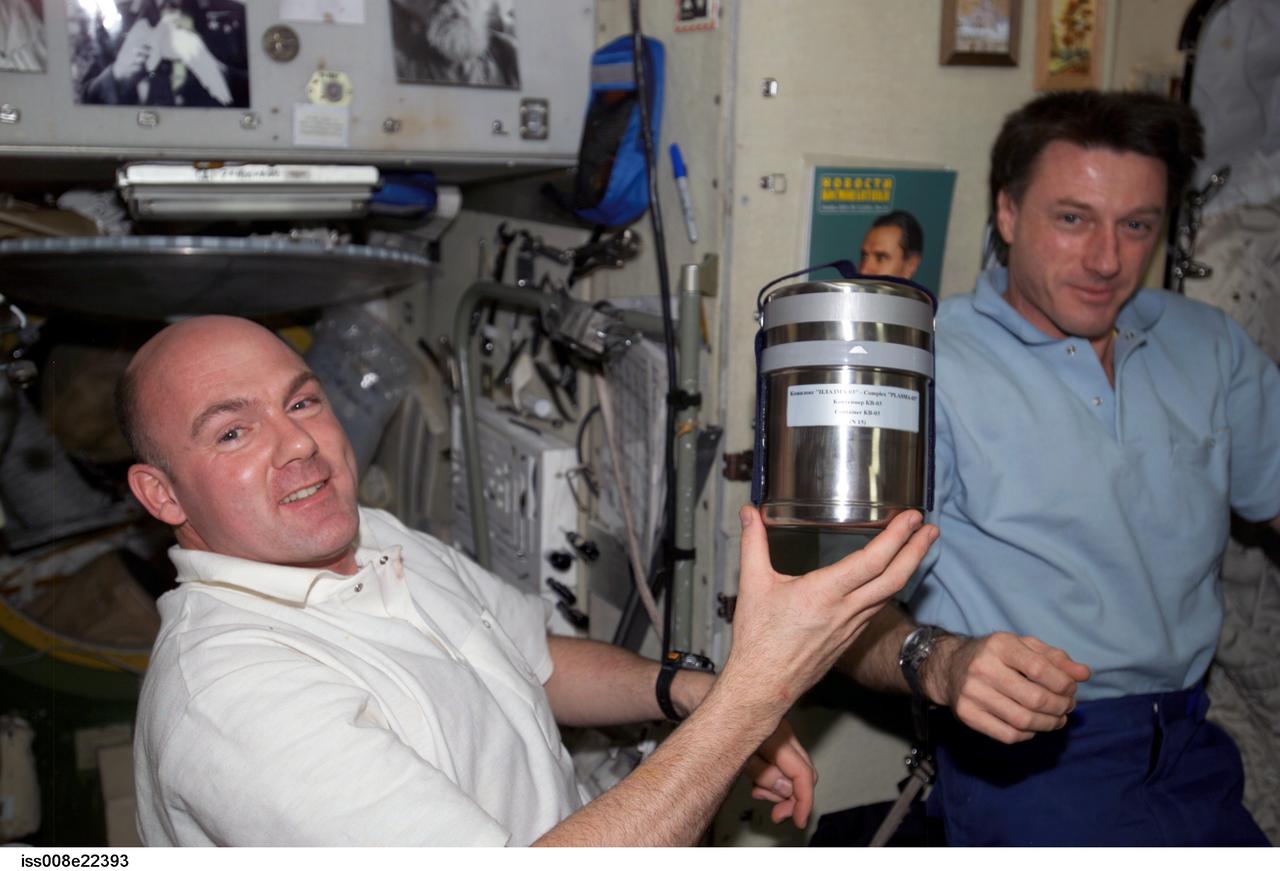 ISS008-E-22393 (29 April 2004) --- European Space Agency (ESA) astronaut Andre Kuipers of the Netherlands, holds a Complex &#0147;Plasma-03&#0148; canister in the Zvezda Service Module of the International Space Station (ISS). Astronaut C. Michael Foale, Expedition 8 commander and NASA ISS science officer, is at right.