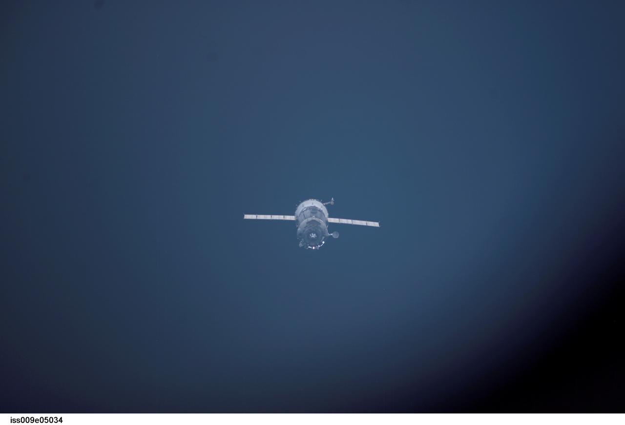 ISS009-E-05034 (29 April 2004) --- As seen through a window on the International Space Station (ISS), the Soyuz TMA-3 capsule departs from the Station carrying astronaut C. Michael Foale, Expedition 8 commander and NASA ISS science officer; cosmonaut Alexander Y. Kaleri, flight engineer representing Russia&#0146;s Federal Space Agency; and European Space Agency (ESA) astronaut Andre Kuipers of the Netherlands. Undocking occurred at 3:52 p.m. (CDT) on April 29.