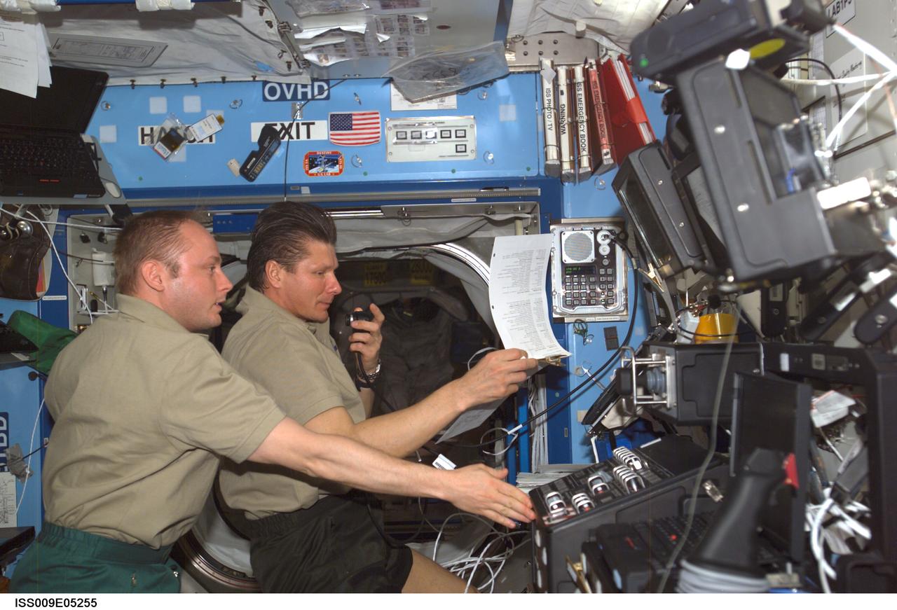 ISS009-E-05255 (1 May 2004) --- Cosmonaut Gennady I. Padalka (right), Expedition 9 commander representing Russia’s Federal Space Agency, looks over a procedures checklist near the Space Station Remote Manipulator System (SSRMS) or Canadarm2 workstation as he talks into a communication system in the Destiny laboratory on the International Space Station (ISS). Astronaut Edward M. (Mike) Fincke, NASA ISS science officer and flight engineer, assisted Padalka.