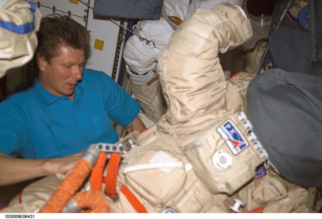 ISS009-E-06431 (10 May 2004) --- Cosmonaut Gennady I. Padalka, Expedition 9 commander representing Russia’s Federal Space Agency, performs a suit check on the Russian Orlan spacesuit in the Unity node of the International Space Station (ISS).