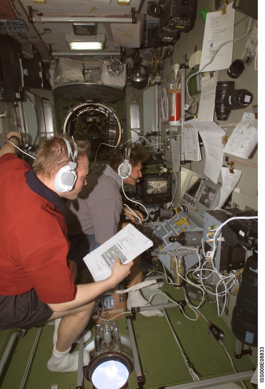 ISS009-E-08833 (27 May 2004) --- Cosmonaut Gennady I. Padalka (background), Expedition 9 commander representing Russia’s Federal Space Agency, works at the Simvol-Ts workstation in the Zvezda Service Module of the International Space Station (ISS) during the docking approach of the Progress 14 spacecraft. Astronaut Edward M. (Mike) Fincke, NASA ISS science officer and flight engineer, assisted Padalka.