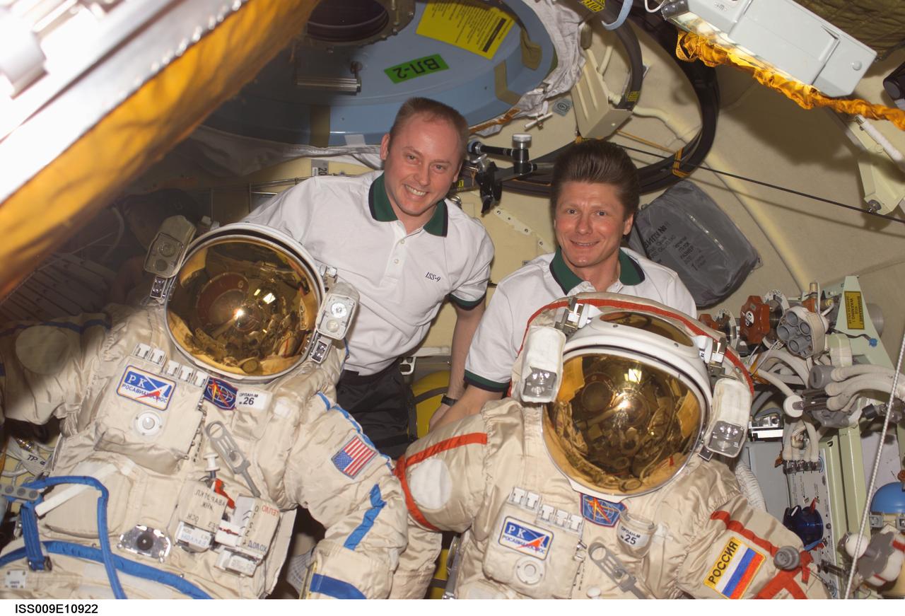 ISS009-E-10922 (10 June 2004) --- Astronaut Edward M. (Mike) Fincke (left), Expedition 9 NASA ISS science officer and flight engineer, and cosmonaut Gennady I. Padalka, commander representing Russia’s Federal Space Agency, pose for a photo with their Russian Orlan spacesuits in the Pirs Docking Compartment of the International Space Station (ISS). Extravehicular activity (EVA) is scheduled for June 24.