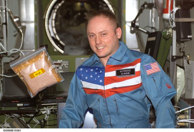 NASA image: Fincke stands beside a floating bag of tomato seeds for the EPO Tomatosphere II project during Expedition 9