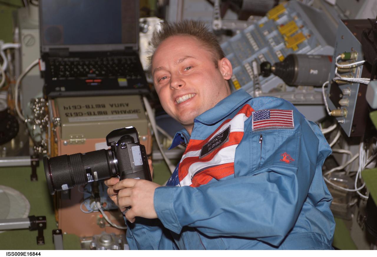 ISS009-E-16844 (29 July 2004) --- Astronaut Edward M. (Mike) Fincke, Expedition 9 NASA ISS science officer and flight engineer, holds a still camera in the Zvezda Service Module on the International Space Station (ISS).