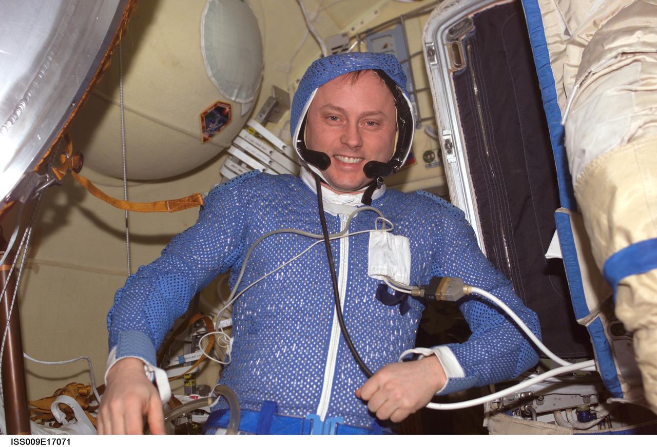 ISS009-E-17071 (30 July 2004) --- Astronaut Edward M. (Mike) Fincke, Expedition 9 NASA ISS science officer and flight engineer, wearing a spacesuit thermal undergarment and communication headgear, poses for a photo in the Pirs Docking Compartment of the International Space Station (ISS).
