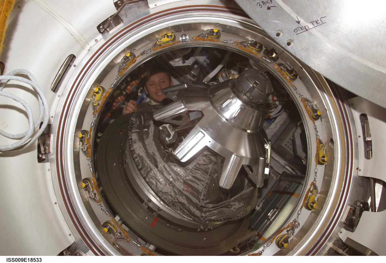 ISS009-E-18533 (14 August 2004) --- Astronaut Edward M. (Mike) Fincke, Expedition 9 NASA ISS science officer and flight engineer, appears behind the probe-and-cone mechanism on the hatch of the Progress 15 supply vehicle docked to the aft port on the Zvezda Service Module of the International Space Station (ISS).