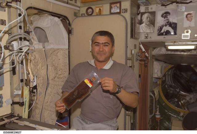 NASA image: Sharipov holds a package of Russian food near the galley in the SM during Expedition 9/10 joint OPS