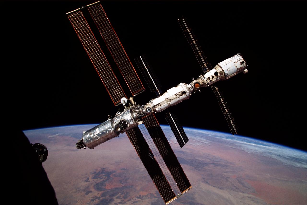 ISS001-389-023 (24 February 2001) --- The International Space Station (ISS), backdropped against the darkness of space and Earth at its horizon, was photographed by the Expedition One crew during a flyaround aboard a Soyuz capsule.