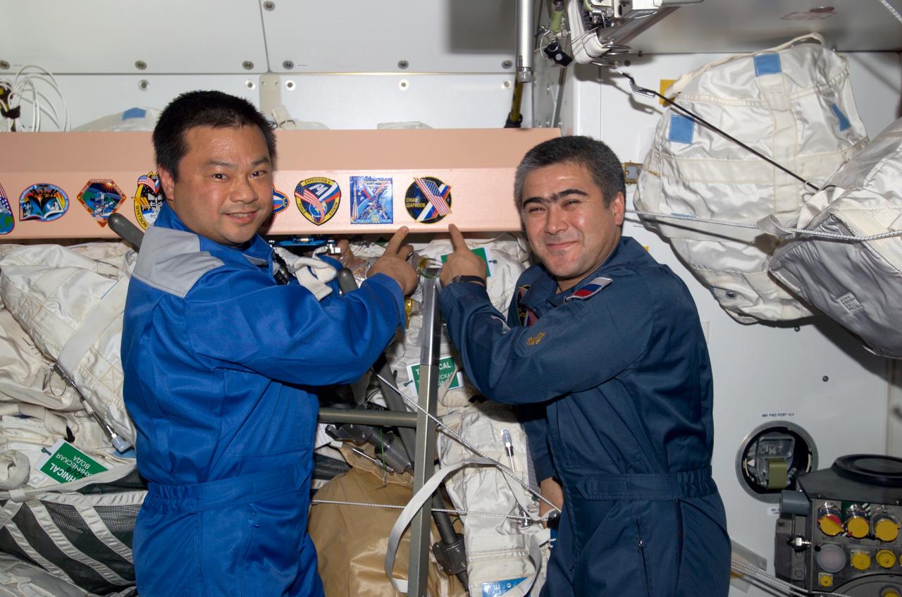 ISS010-E-06019 (6 November 2004) --- Astronaut Leroy Chiao (left), Expedition 10 commander and NASA ISS science officer, and cosmonaut Salizhan S. Sharipov, flight engineer representing Russia's Federal Space Agency, add their crew;s patch to the Unity node;s growing collection of insignias representing crews who have worked on the International Space Station (ISS).