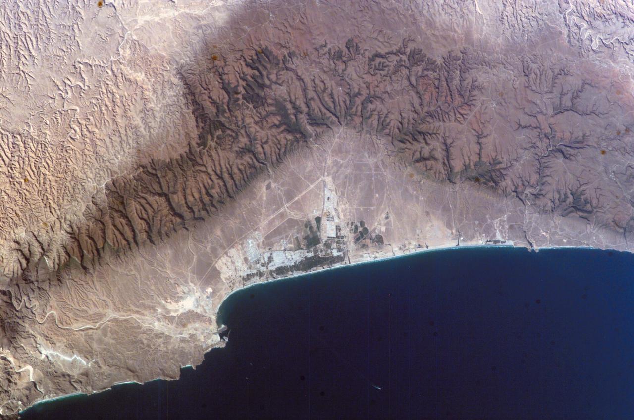 ISS010-E-07210 (16 November 2004) --- Salalah, Sultanate of Oman is featured in this image photographed by an Expedition 10 crewmember on the International Space Station (ISS). The city of Salalah is the capital of the Dhofar region of Oman and is known as the &#0147;perfume capital of Arabia&#0148;. The city is a popular destination for tourism due to the natural attractions of the al Qara Mountains (Jabal al Qara in Arabic) and abundant stands of frankincense trees lining mountain stream courses. These can be seen as green regions in the Jabal al Qara north of the city (located in the center of this image). The beaches and coastline are also major attractions for scuba diving and bird watching. Modern Oman is also represented by the Port of Salalah, located approximately 15 kilometers to the southwest of the city. The strategic location of this port has made it one of the major entry points to India, the Middle East, and Africa. The rectangular projection into the Arabian Sea visible in this photo is a large shipping container loading/unloading platform.