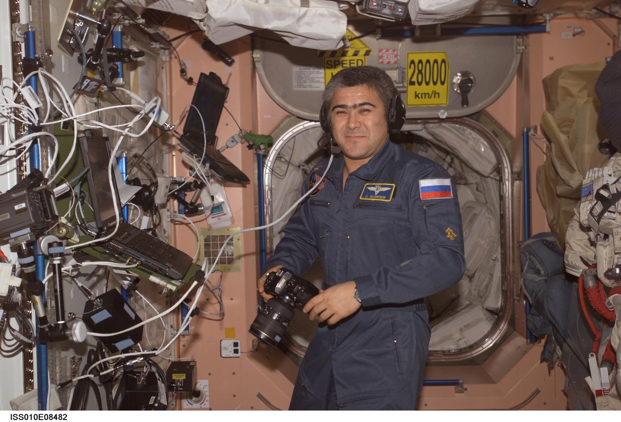 ISS010-E-08482 (23 November 2004) --- Cosmonaut Salizhan S. Sharipov, Expedition 10 flight engineer representing Russia's Federal Space Agency, holds a still camera while using a communication system in the Unity node of the International Space Station (ISS).