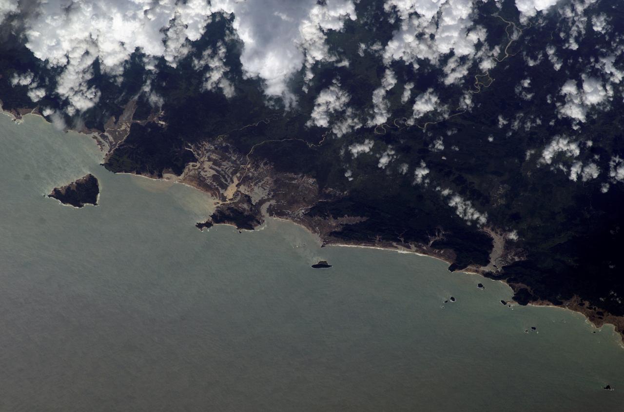 ISS010-E-13088 (15 January 2005) --- Tsunami damage, northwestern Sumatra (Indonesia) is featured in this image photographed by an Expedition 10 crewmember on the International Space Station. On December 26, 2004 a large (magnitude 9.0) earthquake occurred off the western coast of Sumatra in the Indian Ocean. Scientists believe the earthquake was caused by the release of stresses accumulated as the India tectonic plate is overridden by the Burma tectonic plate. Movement of the seafloor due to the earthquake generated a tsunami, or seismic sea wave, that affected coastal regions around the Indian Ocean. The northwestern Sumatra coastline in particular suffered extensive damage and loss of life. This photo, along with image ISS010-E-13079, illustrates damage along the southwestern coast of Aceh Province in the vicinity of the city of Lho&#0146; Kruet, Indonesia. The image captures the sunglint illuminating the Indian Ocean and standing water inland (light gray). Distortion and scale differences are caused by increased obliquity of the view from the Station.