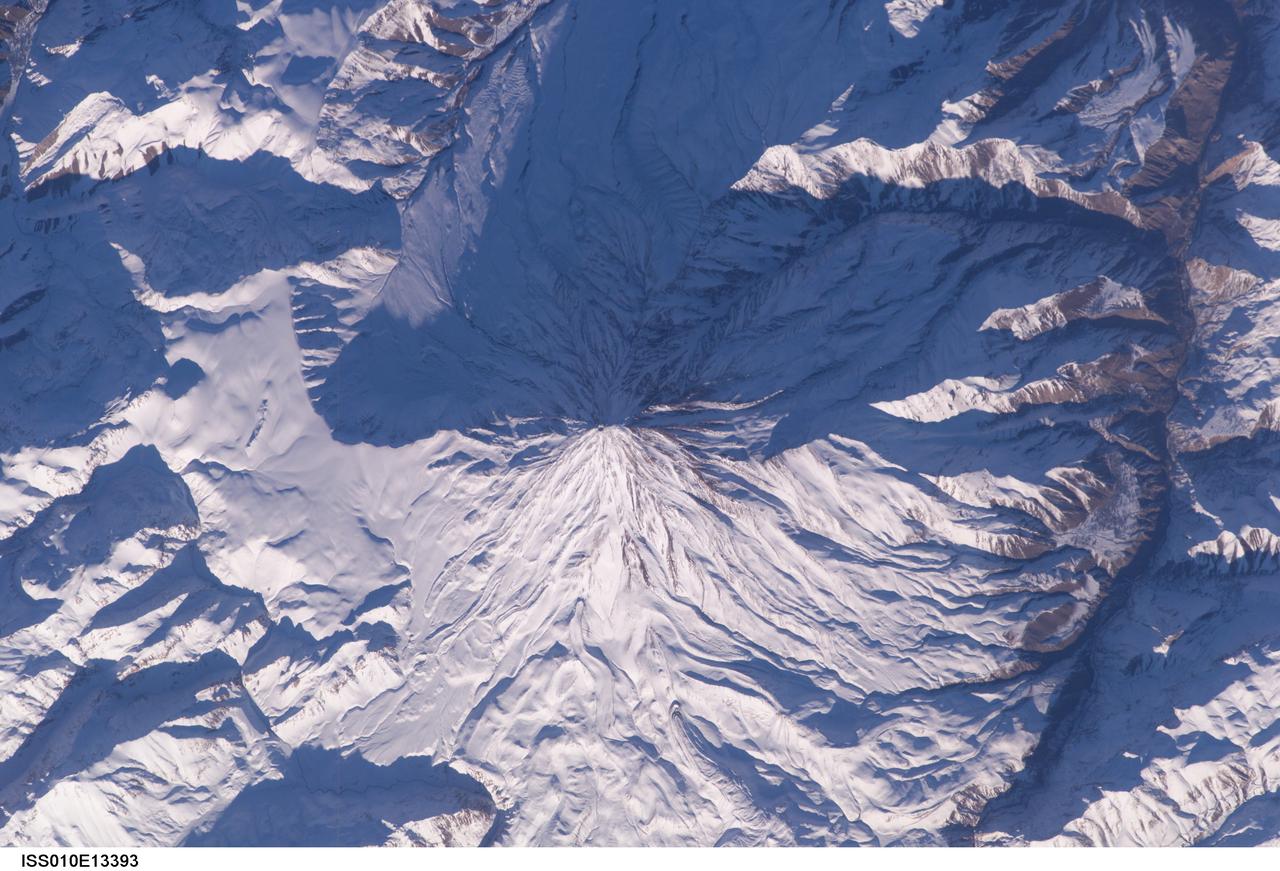 ISS010-E-13393 (15 January 2005) --- Mt. Damavand, Iran is featured in this image photographed by an Expedition 10 crewmember on the International Space Station (ISS). Located approximately 50 kilometers to the northeast of Tehran, Mt. Damavand is an impressive stratovolcano that reaches 5,670 meters (18,598 feet) in elevation. Damavand, which is part of the Alborz mountain range that borders the Caspian Sea to the north, is believed by scientists to be a young volcano that has mostly formed during the Holocene Epoch (over approximately the last 10,000 years). The western flank of the volcano includes solidified lava flows with flow levees – “walls” formed as the side edges of flowing lava cooled rapidly, forming a chute that channeled the hotter interior lava. Two such flows with well-defined levees are highlighted by snow on the mountainside (center). Damavand is the highest peak in Iran and the highest volcano in the Middle East.
