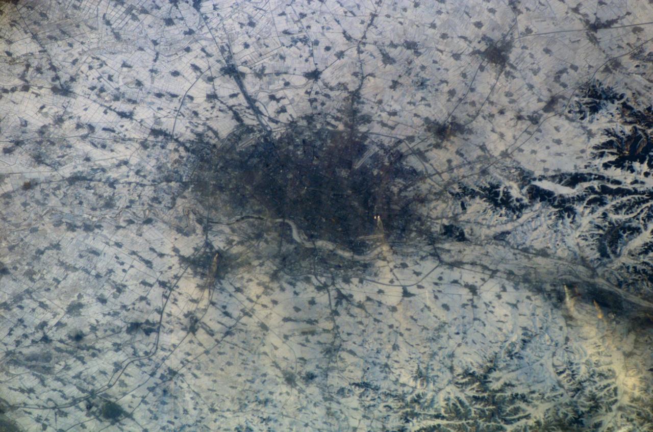 ISS010-E-13807 (18 January 2005) --- Shenyang, China is featured in this image photographed by an Expedition 10 crewmember on the International Space Station (ISS). The city of Shenyang is China&#0146;s sixth largest city with a population of over 4 million residents in the urban core. The city is the major industrial, commercial, and cultural center of northeast China (the region historically known as Manchuria). Its geographic location on the floodplains of the Hun and Liao Rivers ensured an early agrarian economy that was later replaced by industrialization and natural resource extraction. Shenyang was first settled as a Mongol trading center in the 10th century, and served as the capitol of the Manchu government from the 17th through 20th centuries. Currently the city serves as the capital of Liaoning Province. Snow cover provides a clear contrast between urbanized (dark grey, center of image) and rural regions (white to light grey). The major portion of the local economy is devoted to industries such as metal smelting, coal mining, and petrochemical processing. Several southeast-trending plumes from industrial facilities are visible in the image. According to NASA scientists studying the Expedition 10 imagery, the high density of industrial land use in the Shenyang metropolitan area has lead to significant air, water, and soil pollution in the region. Recently, several initiatives to reduce pollution levels and establish environmentally-sound development guidelines have begun with support from local government and the United Nations.