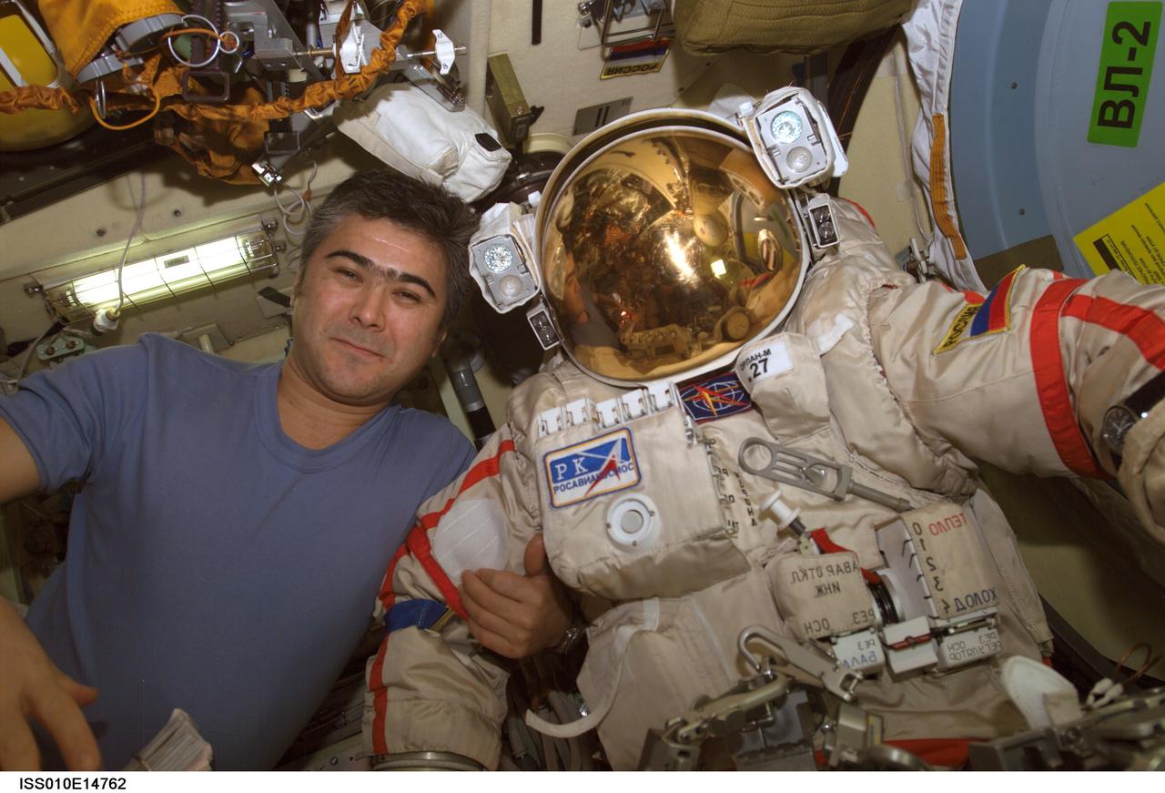ISS010-E-14762 (24 January 2005) --- Cosmonaut Salizhan S. Sharipov, Expedition 10 flight engineer representing Russia's Federal Space Agency, poses with his Russian Orlan spacesuit in the Pirs Docking Compartment of the International Space Station (ISS). Sharipov and astronaut Leroy Chiao (out of frame), commander and NASA ISS science officer, were conducting extravehicular activity (EVA) preparations for the spacewalk scheduled for January 26.