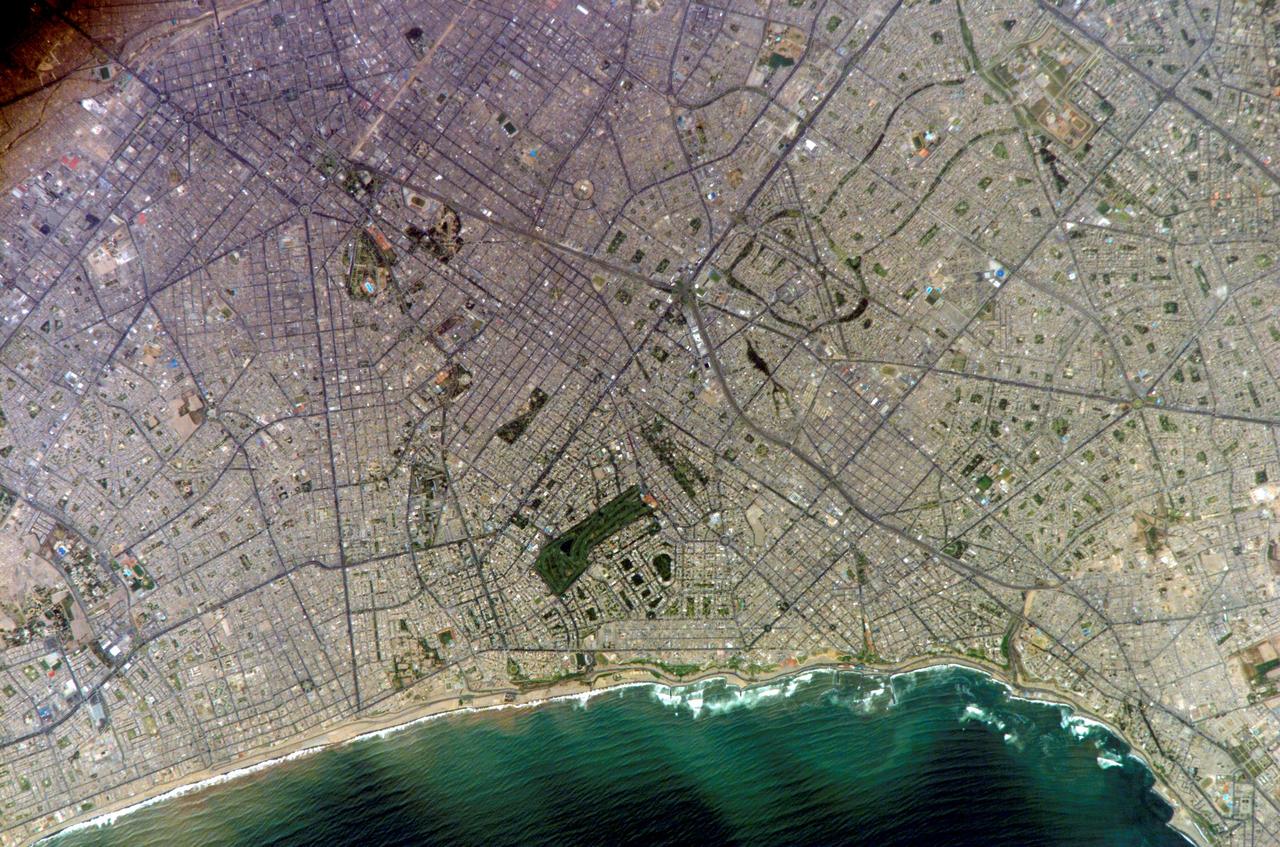 ISS010-E-20111 (15 March 2005) --- Lima, Peru is featured in this image photographed by an Expedition 10 crewmember on the International Space Station (ISS). Located on the broad alluvial fan of the Rimac River, Lima is the capital of Peru and the only mega city (7.7 million inhabitants in 2002) located on the western coastline of South America. The city was established by Francisco Pizarro in 1535 and became an important colonial port linking silver mines of the Altiplano of the high Andes to the east with the burgeoning Spanish empire. During the mid-20th century a significant relocation of people from rural mountain communities into the Lima metropolitan area led to its growth into a mega city. Problems now facing the metropolitan region include development of adequate water resources, control of pollution, and the potential effects of natural hazards such as earthquakes and landslides. This photograph depicts the wealthier San Isidro and Mira Flores quarters of Lima. This part of the metropolitan area is characterized by numerous vegetated parks, golf courses (such as the Lima Golf Course—approximately 1 kilometer long), and greenbelts interspersed with residential and commercial areas. The higher proportion of dark asphalt in the street grid of the residential and commercial areas lends a purple coloration to the left portion of the image (downtown Lima is to the north). Regions with fewer built materials and vegetation are light tan. Wave patterns are visible approaching beaches, popular tourist destinations, in the lower half of the image.