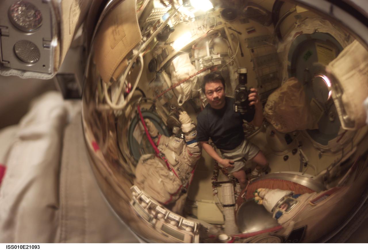 ISS010-E-21093 (22 March 2005) --- Astronaut Leroy Chiao, Expedition 10 commander and NASA ISS science officer, appears as a small reflection in a helmet visor in the Pirs Docking Compartment of the International Space Station (ISS).
