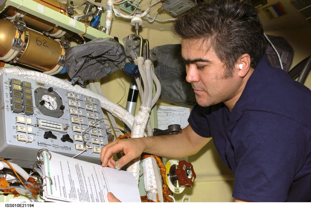 ISS010-E-21194 (23 March 2005) --- Cosmonaut Salizhan S. Sharipov, Expedition 10 flight engineer representing Russia's Federal Space Agency, looks over a procedures checklist while working with the Russian Orlan Interface Unit in the Pirs Docking Compartment of the International Space Station (ISS). The final spacewalk for Expedition 10 is scheduled for March 28.