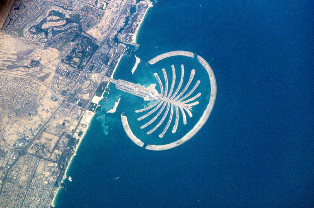 ISS010-E-22273 (1 April 2005) --- Palm Island Resort, Dubai, United Arab Emirates is featured in this image photographed by an Expedition 10 crewmember on the International Space Station. Palm Island is a resort under construction on reclaimed land silhouetted against the dark waters of Dubai&#0146;s Persian Gulf coast. Advertised as "being visible from the Moon," this man-made palm-shaped structure displays 17 huge fronds framed by a 12-kilometer protective barrier. When completed, the resort will sport 2000 villas, 40 luxury hotels, shopping centers, cinemas, and other facilities. An earlier handheld image from 2003 shows the outline of the palm nearing completion (link to http://spaceflight.nasa.gov/gallery/images/station/crew-6/html/iss006e35516.html). Two years later, the palm appears in all its glory to passing space travelers. It has so far required over 50 million cubic meters of sand to raise it above the sea surface. Palm Island is the last of three major developments designed to transform the Dubai coastline into a major coastal metropolitan area and destination. When completed, the resort is expected to support a population of approximately 500,000 people.