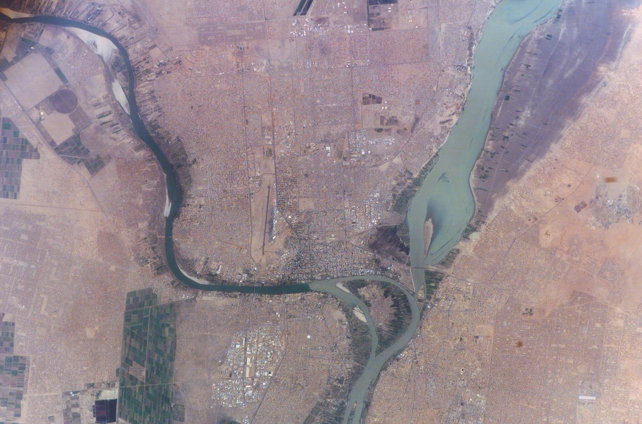 ISS010-E-23451 (7 April 2005) --- Khartoum, Sudan is featured in this image photographed by an Expedition 10 crewmember on the International Space Station (ISS). Sudan’s capital city Khartoum, which means Elephant’s Trunk, describes the shape of the Nile River where the Blue and the White Nile Rivers meet to form the united Nile that flows northward into Egypt. This image shows the rivers near the end of the dry season. The White Nile (western branch) runs through Sudan from Uganda. The White Nile’s equatorial source produces a flow that runs at a nearly constant rate throughout the year. The nearly dry Blue Nile from the highlands of Ethiopia swells in the late summer and early fall with rains from the summer monsoons. The flow can be so great the Nile flows backward at the junction. In recent years, floods in Khartoum have occurred in August with heavy monsoon rainfall. Khartoum is one of the largest Muslim cities in North Africa, but has a fairly short history.