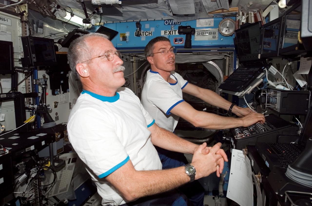 ISS010-E-24987 (19 April 2005) --- Cosmonaut Sergei K. Krikalev (background), Expedition 11 commander representing Russia's Federal Space Agency, and astronaut John L. Phillips, NASA science officer and flight engineer, participate in a familiarization session with the Mobile Service System (MSS) and hands-on experience with the Canadarm2, or Space Station Remote Manipulator System (SSRMS) in the Destiny laboratory of the international space station. The two new arrivals are scheduled to spend several months aboard the orbital outpost. Krikalev will be the first station inhabitant to serve two terms onboard.
