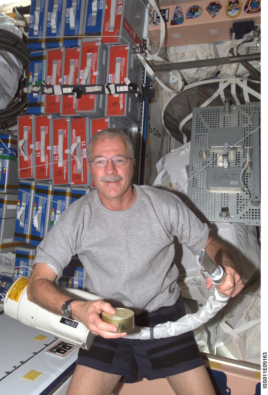 ISS011-E-05163 (17 April 2005) --- Astronaut John L. Phillips, Expedition 11 NASA ISS science officer and flight engineer, poses for a photo with the ISS wet/dry vacuum cleaner assembly he used to catch floating debris from the top of a food can in the Unity node of the International Space Station (ISS).