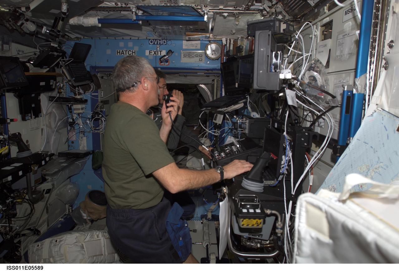 ISS011-E-05589 (6 May 2005) --- Astronaut John L. Phillips, Expedition 11 NASA ISS science officer, and cosmonaut Sergei K. Krikalev (obscured), commander representing Russia's Federal Space Agency, participate in a proficiency training session with the Canadarm2, or Space Station Remote Manipulator System (SSRMS) in the Destiny laboratory of the International Space Station (ISS).