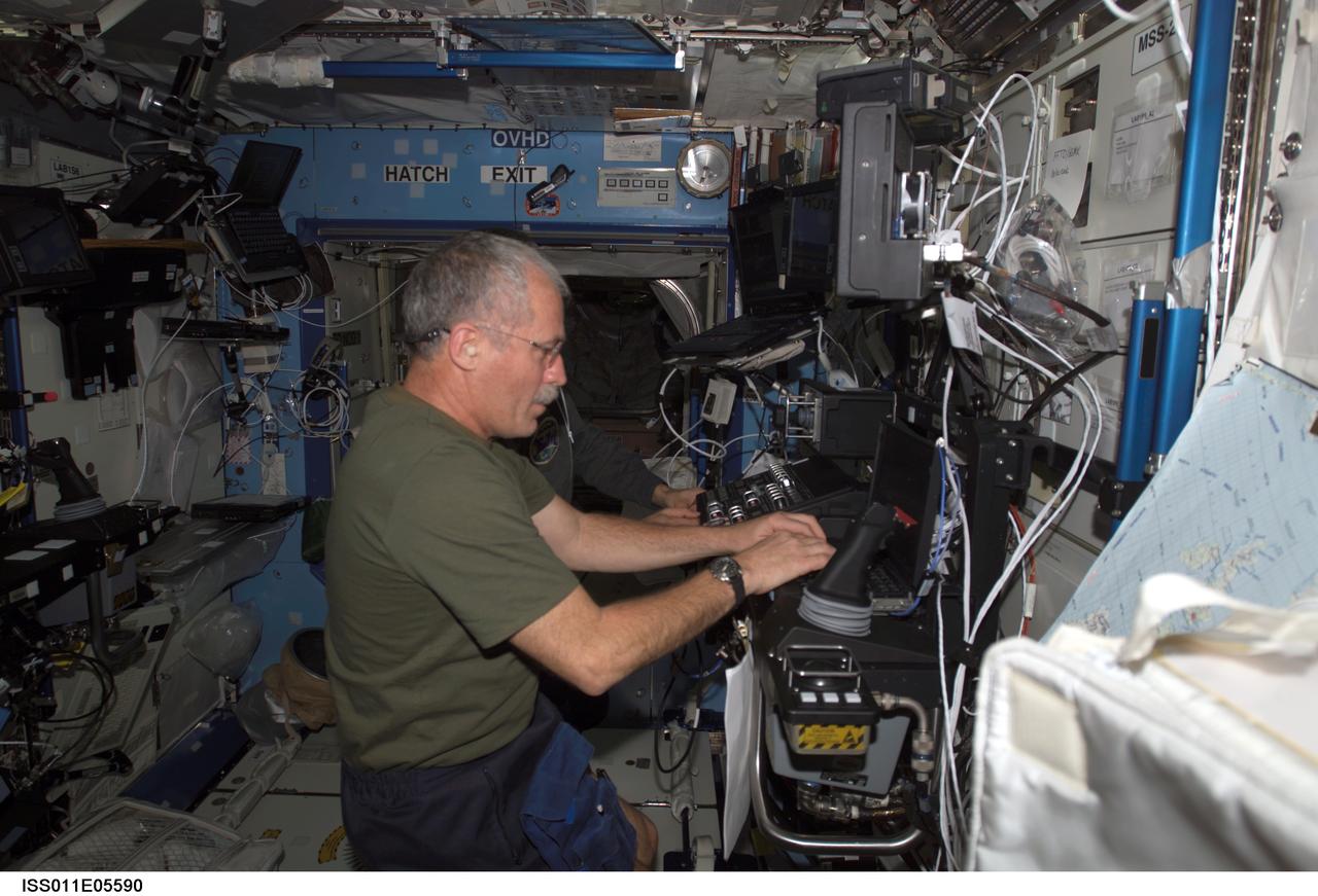 ISS011-E-05590 (6 May 2005) --- Astronaut John L. Phillips, Expedition 11 NASA ISS science officer, and cosmonaut Sergei K. Krikalev (obscured), commander representing Russia's Federal Space Agency, participate in a proficiency training session with the Canadarm2, or Space Station Remote Manipulator System (SSRMS) in the Destiny laboratory of the International Space Station (ISS).