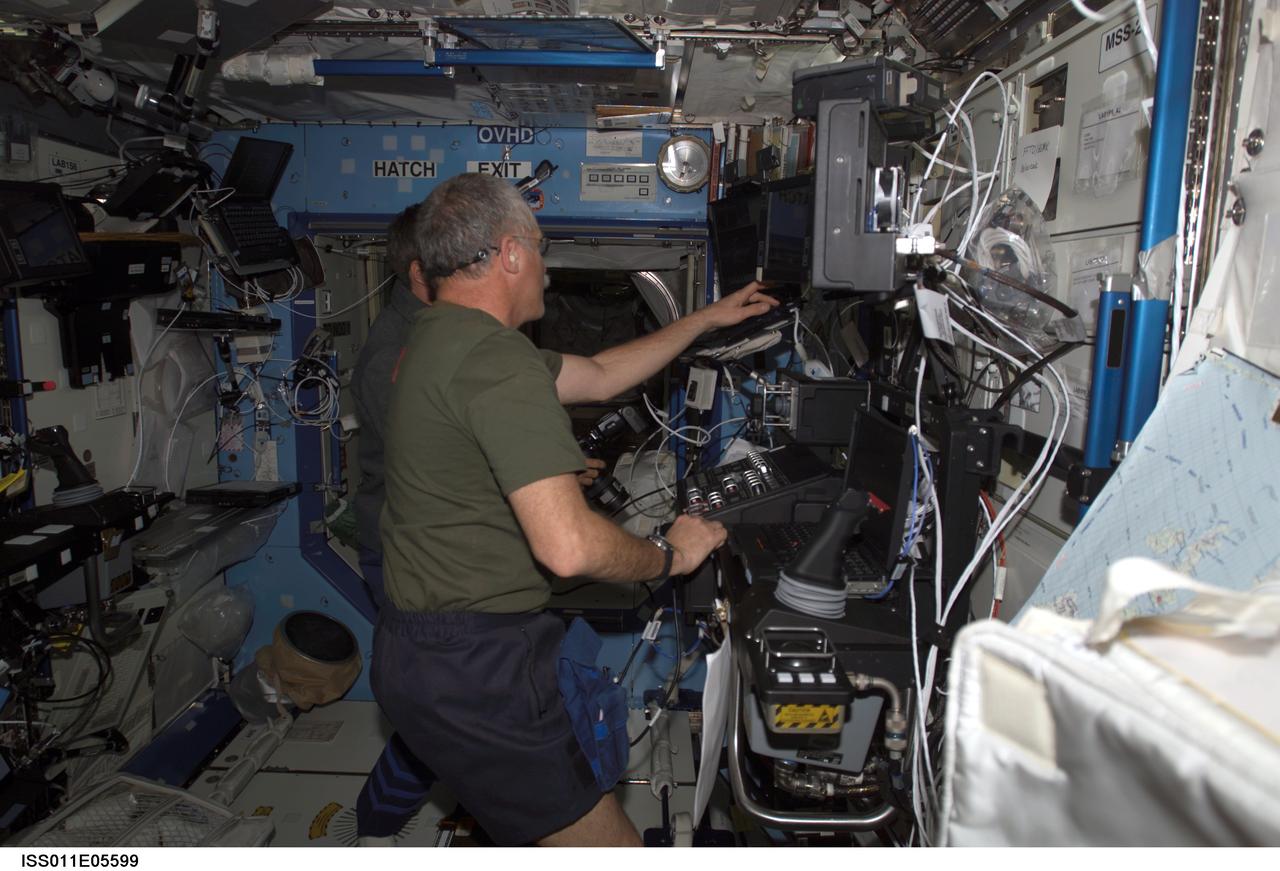 ISS011-E-05599 (6 May 2005) --- Astronaut John L. Phillips, Expedition 11 NASA ISS science officer, and cosmonaut Sergei K. Krikalev (obscured), commander representing Russia's Federal Space Agency, participate in a proficiency training session with the Canadarm2, or Space Station Remote Manipulator System (SSRMS) in the Destiny laboratory of the International Space Station (ISS).