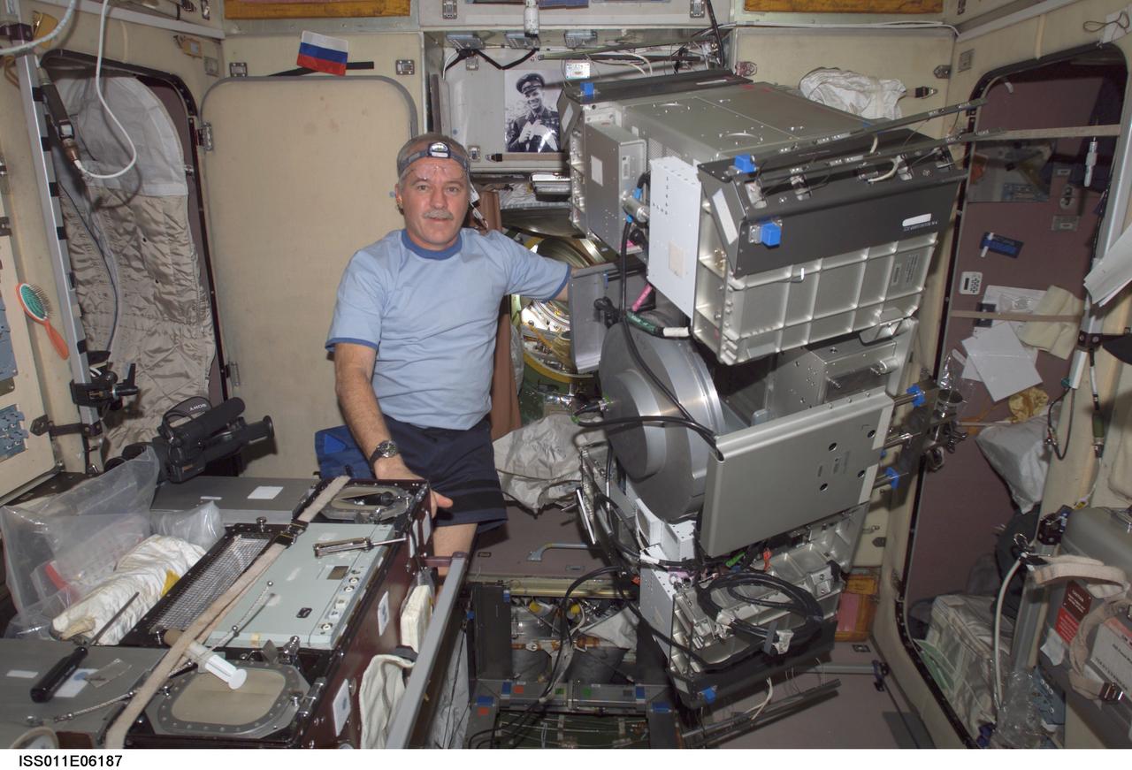 ISS011-E-06187 (16 May 2005) --- Astronaut John L. Phillips, Expedition 11 NASA ISS science officer and flight engineer, poses for a photo with the Treadmill Vibration Isolation System (TVIS) removed from the Zvezda Service Module floor during an In-Flight Maintenance (IFM) on the International Space Station (ISS).
