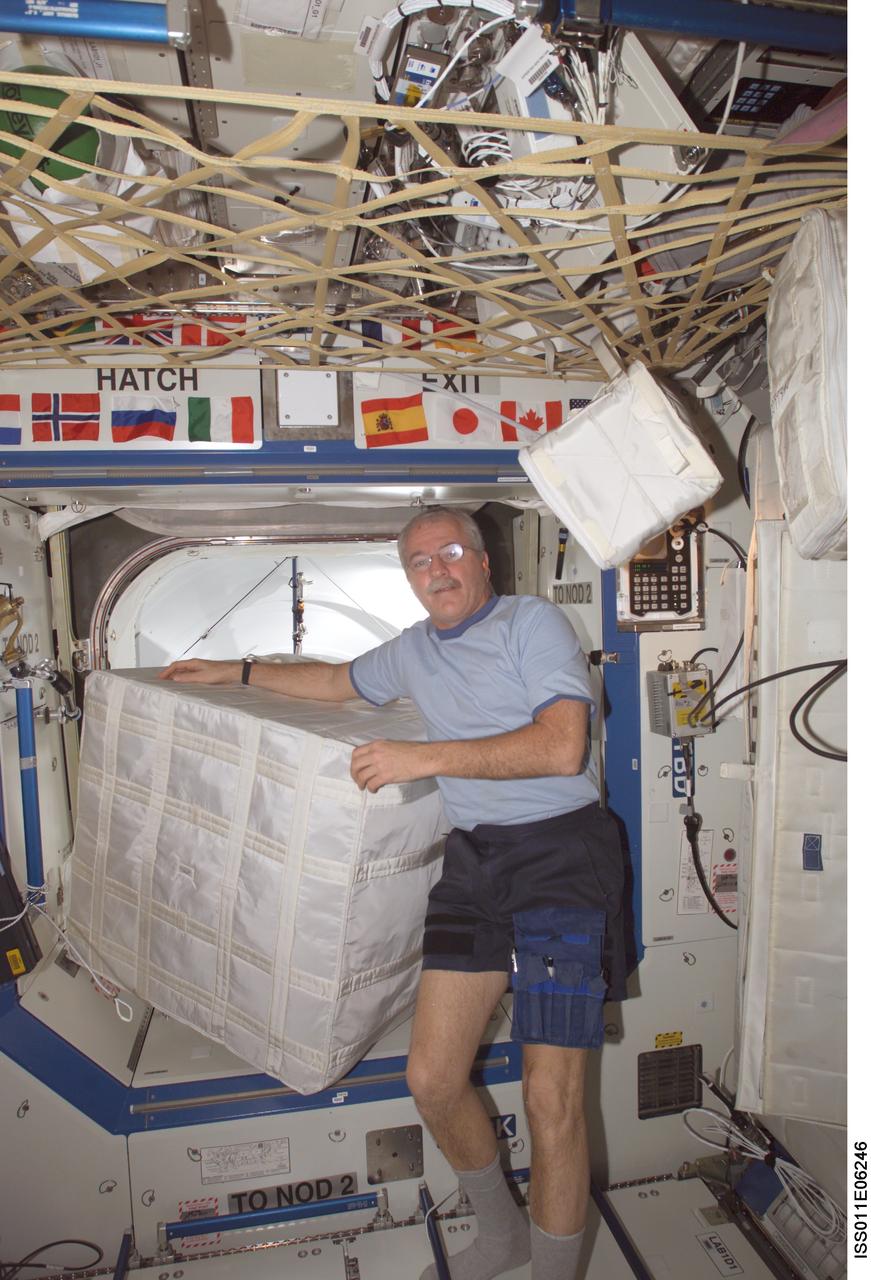 ISS011-E-06246 (18 May 2005) --- Astronaut John L. Phillips, Expedition 11 NASA ISS science officer and flight engineer, moves un-stowed cargo from the PMA-2 (Pressurized Mating Adapter-2) in preparation for the scheduled docking of the Space Shuttle Discovery. Phillips is in the Destiny laboratory of the International Space Station (ISS) with the hatch leading to the adapter in the background.