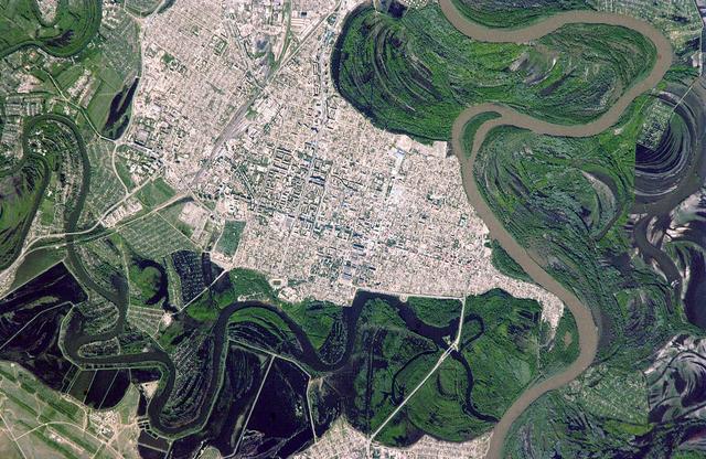 ISS011-E-06712 (22 May 2005) --- Uralsk, Kazakhstan is featured in this image photographed by an Expedition 11 crew member on the international space station. The rough boundary between Europe and Asia is defined by the Ural River and the Ural Mountains to its north. The Ural River flows to the great inland Caspian Sea, and gives its name to the major city of Uralsk (population approximately 250,000) on its banks. Lying just inside the Kazakh border with Russia, Uralsk is an agricultural and industrial center, and important trade stop since the early 1600s. Barge traffic has passed up and down the Ural River between the Caspian Sea and the Ural Mountains for centuries. Today it is one of the major entry points for rail traffic from Europe to Siberia, servicing the many new oil fields in the Caspian basin and the industrial cities of the southern Urals. Numerous details are visible in the photo, including the city margin, city blocks and even the causeway and individual buildings. Part of the smaller sister city of Zashaghan can be seen on the opposite bank (bottom). The green vegetated parts of the floodplains and black inundated parts (lower left, bottom image) stand out clearly. The brown Ural River waters contrast with the darker color of its tributary, the Chogan River (lower image).