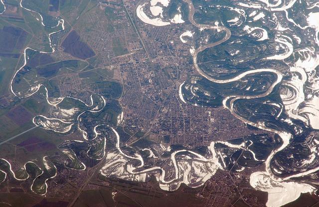 ISS011-E-06717 (22 May 2005) --- Uralsk, Kazakhstan is featured in this image photographed by an Expedition 11 crew member on the international space station. The rough boundary between Europe and Asia is defined by the Ural River and the Ural Mountains to its north. The Ural River flows to the great inland Caspian Sea, and gives its name to the major city of Uralsk (population approximately 250,000) on its banks. Lying just inside the Kazakh border with Russia, Uralsk is an agricultural and industrial center, and important trade stop since the early 1600s. Barge traffic has passed up and down the Ural River between the Caspian Sea and the Ural Mountains for centuries. Today it is one of the major entry points for rail traffic from Europe to Siberia, servicing the many new oil fields in the Caspian basin and the industrial cities of the southern Urals. This view shows the sunglint (light reflected from the water surface towards the observer) on the rivers, lakes and ponds of the Ural floodplain (right side of image) and that of a tributary, the Chogan River (left side of image). The cityscape of Uralsk, on the headland between the two, is relatively difficult to see because the water and sunglint dominate the scene.