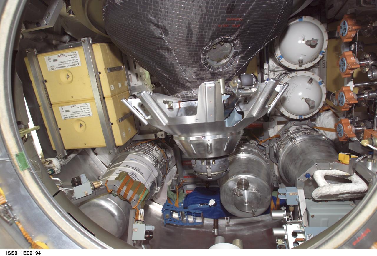 ISS011-E-09194 (19 June 2005) --- View of stowage items and the probe-and-cone docking mechanism in the hatch of the Progress 18 resupply craft, which docked to the aft port of the Zvezda Service Module of the International Space Station at 7:42 p.m. (CDT) on June 18 as the station flew approximately 225 statute miles above a point near Beijing, China. Progress delivered two tons of supplies, food, water, fuel and equipment to the Expedition 11 crewmembers onboard the station.