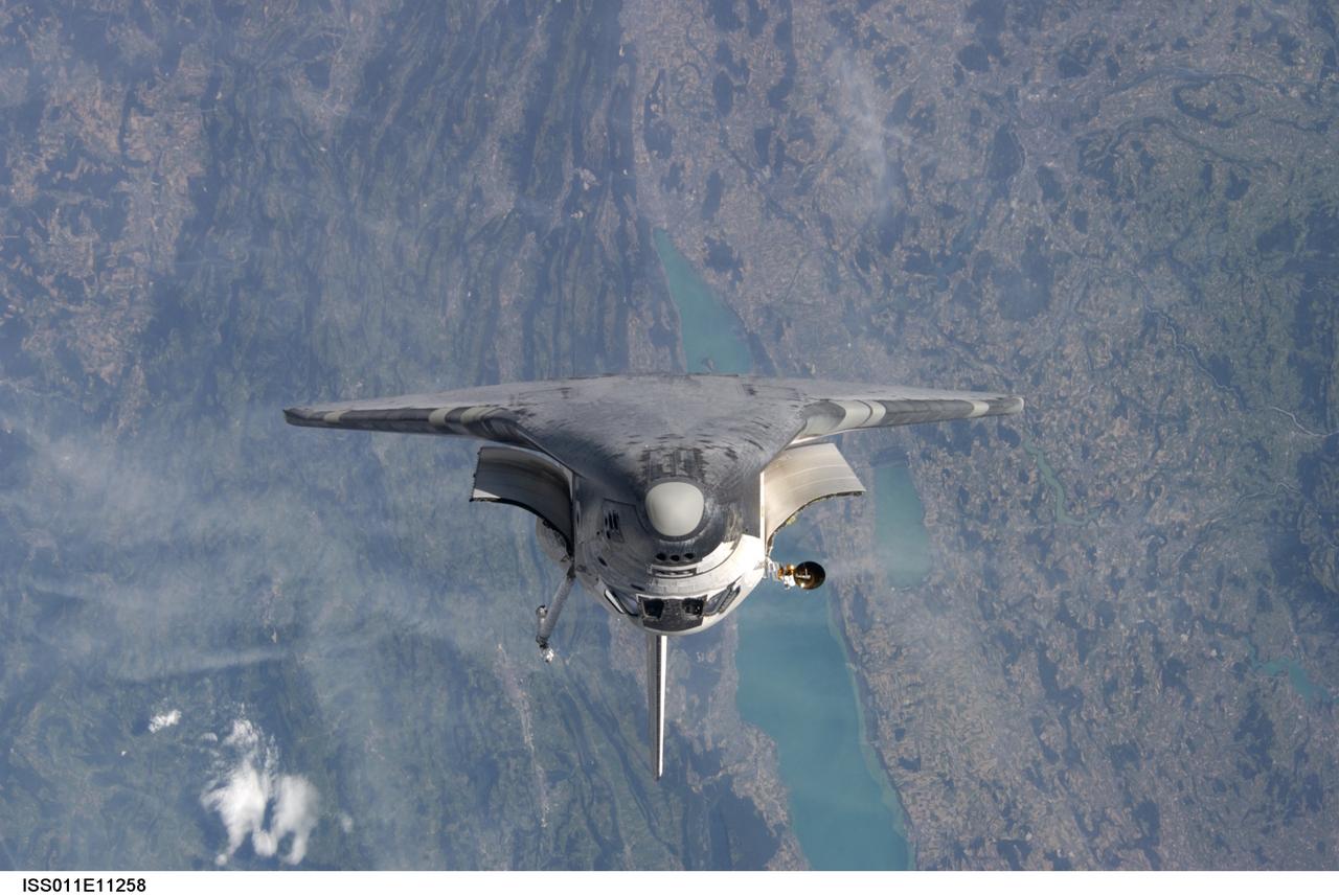 ISS011-E-11258 (28 July 2005) --- View of the Space Shuttle Discovery as photographed during the survey operations performed by the Expedition 11 crew on the International Space Station during the STS-114 R-Bar Pitch Maneuver on Flight Day 3. Discovery docked to the station at 6:18 a.m. (CDT) on Thursday, July 28, 2005. Parts of Switzerland are in the background. Onboard the shuttle were astronauts Eileen M. Collins, STS-114 commander; James M. Kelly, pilot; Andrew S. W. Thomas, Stephen K. Robinson, Wendy B. Lawrence, Charles J. Camarda and Japan Aerospace Exploration Agency (JAXA) astronaut Soichi Noguchi, all mission specialists.