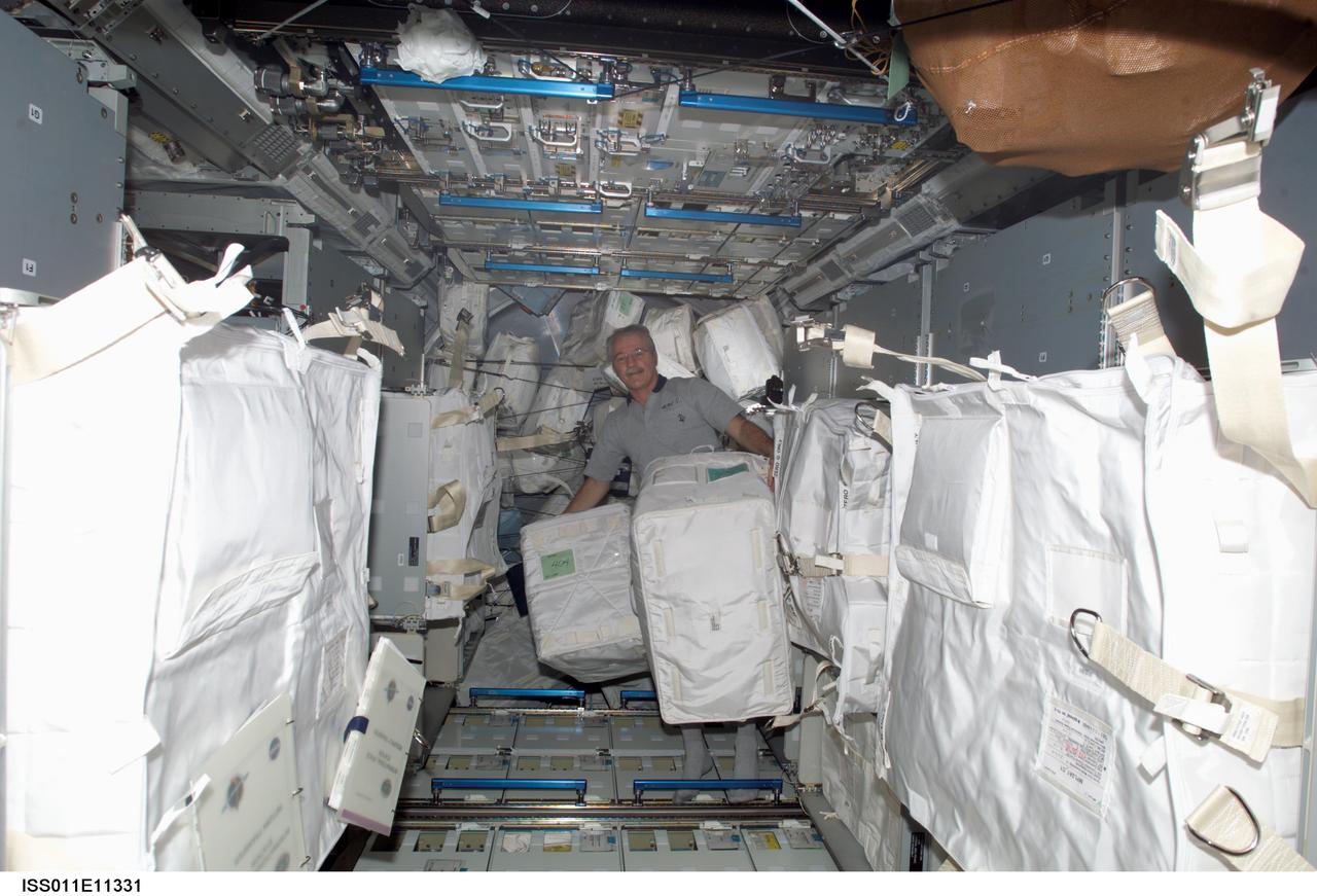 ISS011-E-11331 (30 July 2005) --- Astronaut John L. Phillips, Expedition 11 NASA space station science officer and flight engineer, retrieves supplies from the Raffaello Multi-Purpose Logistics Module (MPLM), which was brought to Earth-orbit by the seven-member STS-114 crew of the space shuttle Discovery.