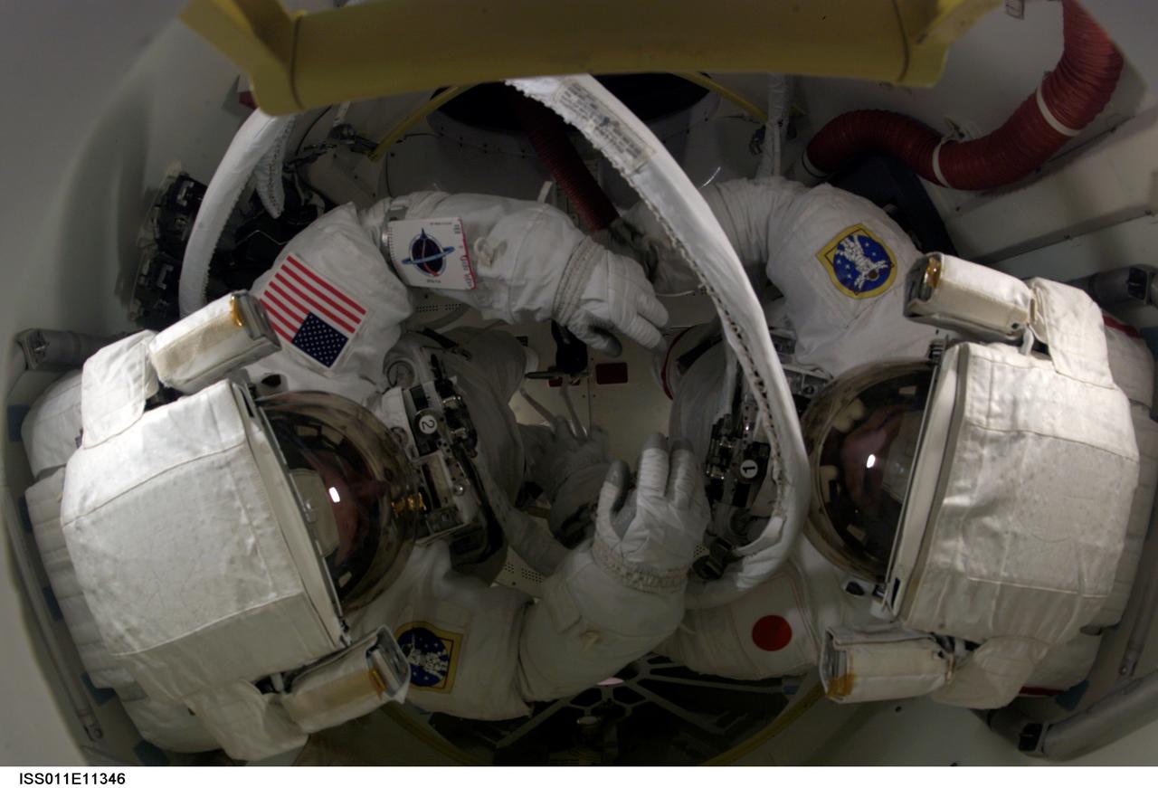 ISS011-E-11346 (30 July 2005) --- Astronaut Stephen K. Robinson, left, and Japanese Aerospace Agency astronaut Soichi Noguchi prepare for the first of three STS-114 spacewalks in the Space Shuttle Discovery's airlock.