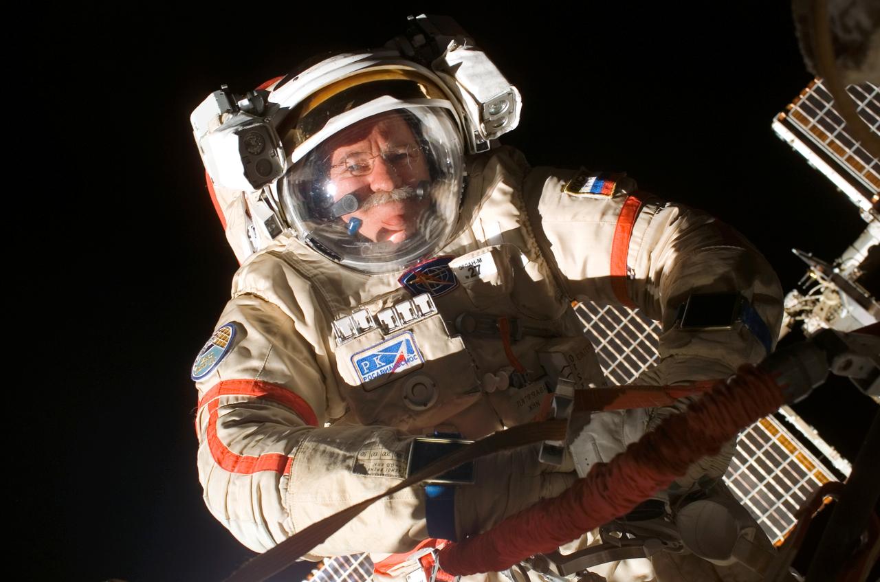 ISS011-E-11944 (18 August 2005) --- Attired in a Russian Orlan spacesuit, astronaut John L. Phillips, Expedition 11 NASA science officer and flight engineer, participates in a session of extravehicular activity (EVA). The 4 hour 58 minute spacewalk by Phillips and cosmonaut Sergei K. Krikalev (out of frame), commander representing Russia's Federal Space Agency, was the 62nd EVA in support of station assembly and maintenance, the 34th conducted from the station itself, and the 16th from the Pirs Docking Compartment.