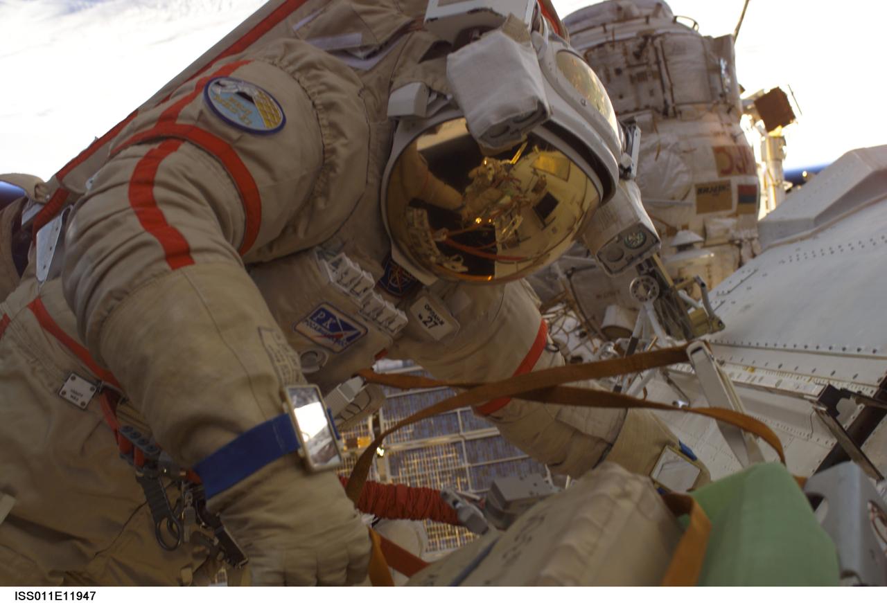 ISS011-E-11947 (18 August 2005) --- Attired in a Russian Orlan spacesuit, astronaut John L. Phillips, Expedition 11 NASA Space Station science officer and flight engineer, participates in a session of extravehicular activity (EVA). The 4 hour 58 minute spacewalk by Phillips and cosmonaut Sergei K. Krikalev (seen in Phillip;s helmet visor), commander representing Russia's Federal Space Agency, was the 62nd EVA in support of Station assembly and maintenance, the 34th conducted from the Station itself, and the 16th from the Pirs Docking Compartment.