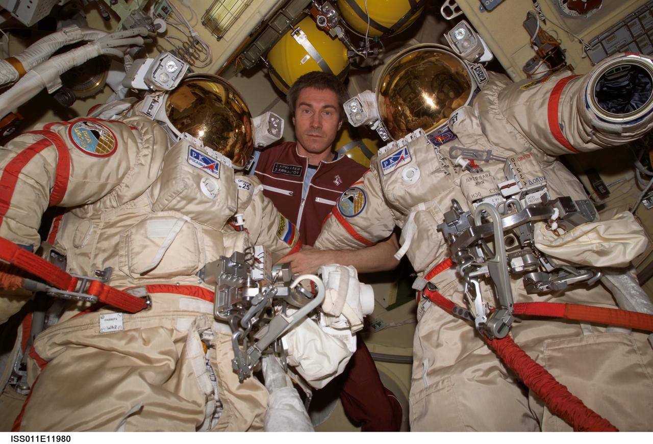 ISS011-E-11980 (17 August 2005) --- Cosmonaut Sergei K. Krikalev, Expedition 11 commander representing Russia's Federal Space Agency, poses with Russian Orlan spacesuits in the Pirs Docking Compartment of the International Space Station. The mission;s first spacewalk is scheduled for August 18.
