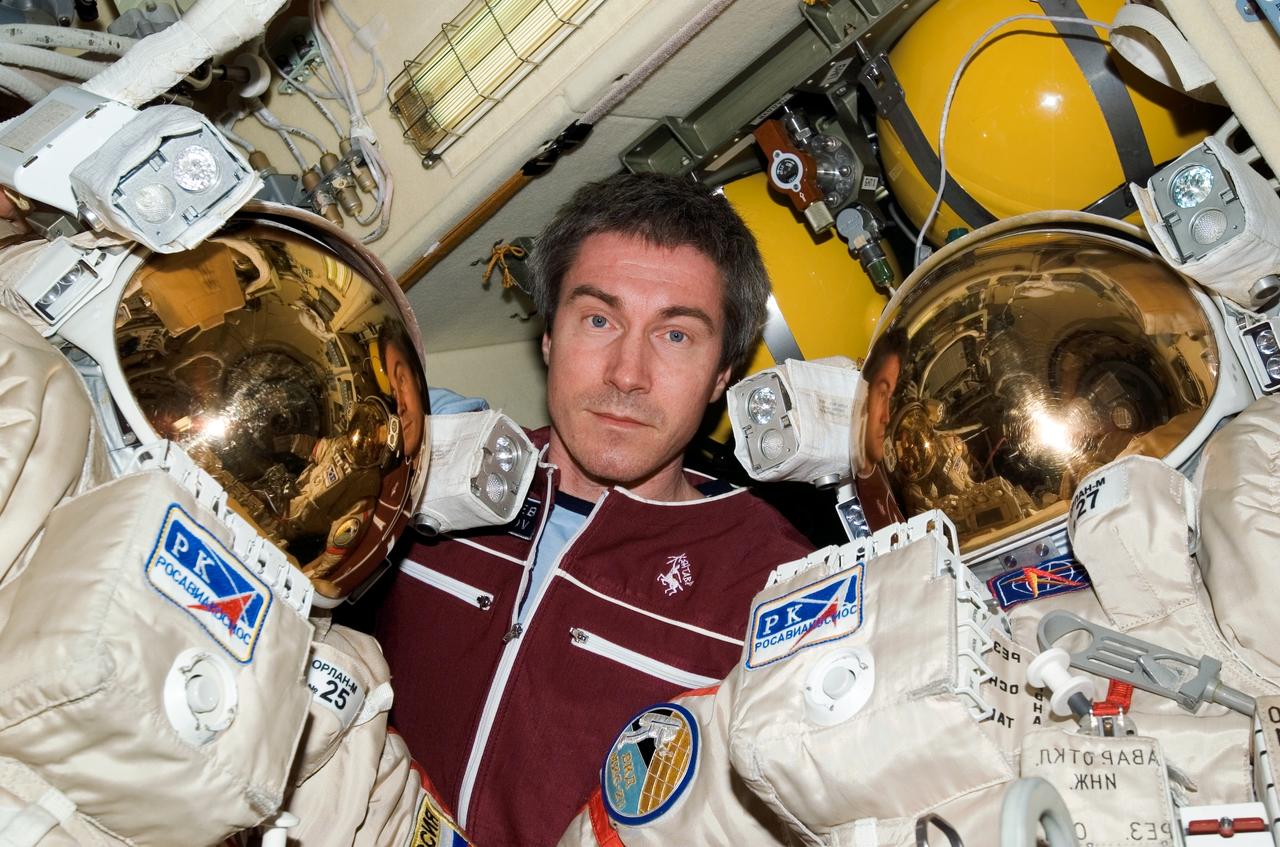 ISS011-E-11984 (17 August 2005) --- Cosmonaut Sergei K. Krikalev, Expedition 11 commander representing Russia's Federal Space Agency, poses with Russian Orlan spacesuits in the Pirs Docking Compartment of the international space station. The mission&#0146;s first spacewalk is scheduled for August 18.